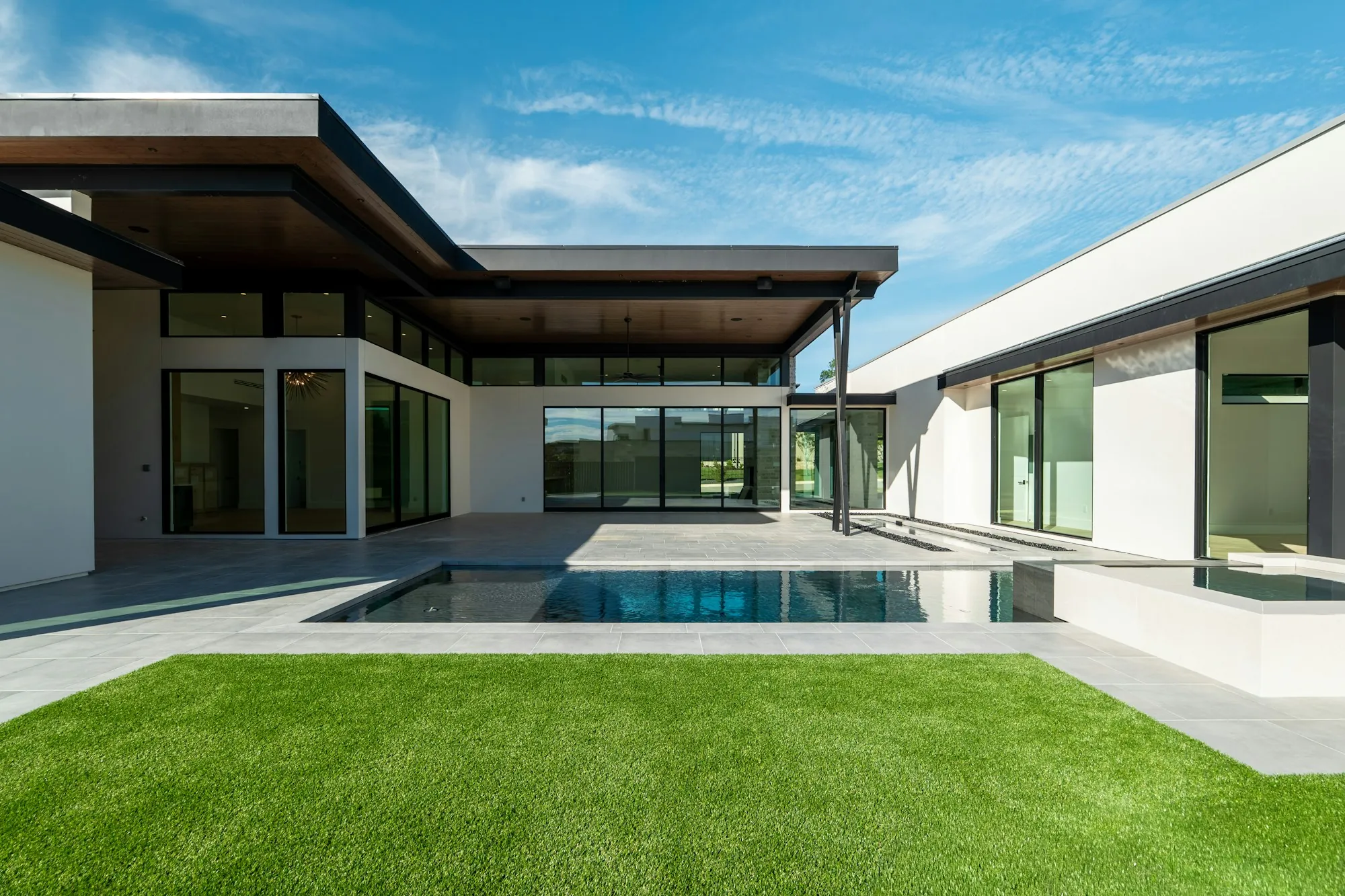 Modern home with a concrete pool deck and lawn
